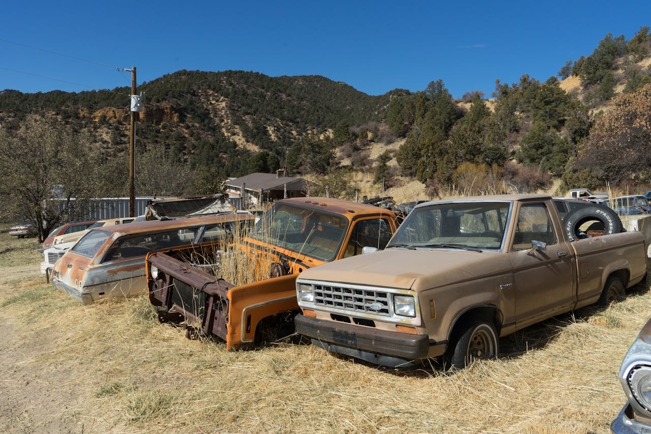 services-04 A collection of vintage vehicles rusting in a rural American junkyard.